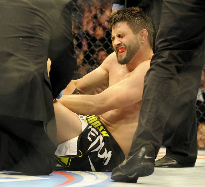 Carlos Condit is tended to by doctors after being injured during a UFC 171 mixed martial arts welterweight bout against Tyron Woodley, Saturday, March. 15, 2014, in Dallas. Woodley won by TKO.